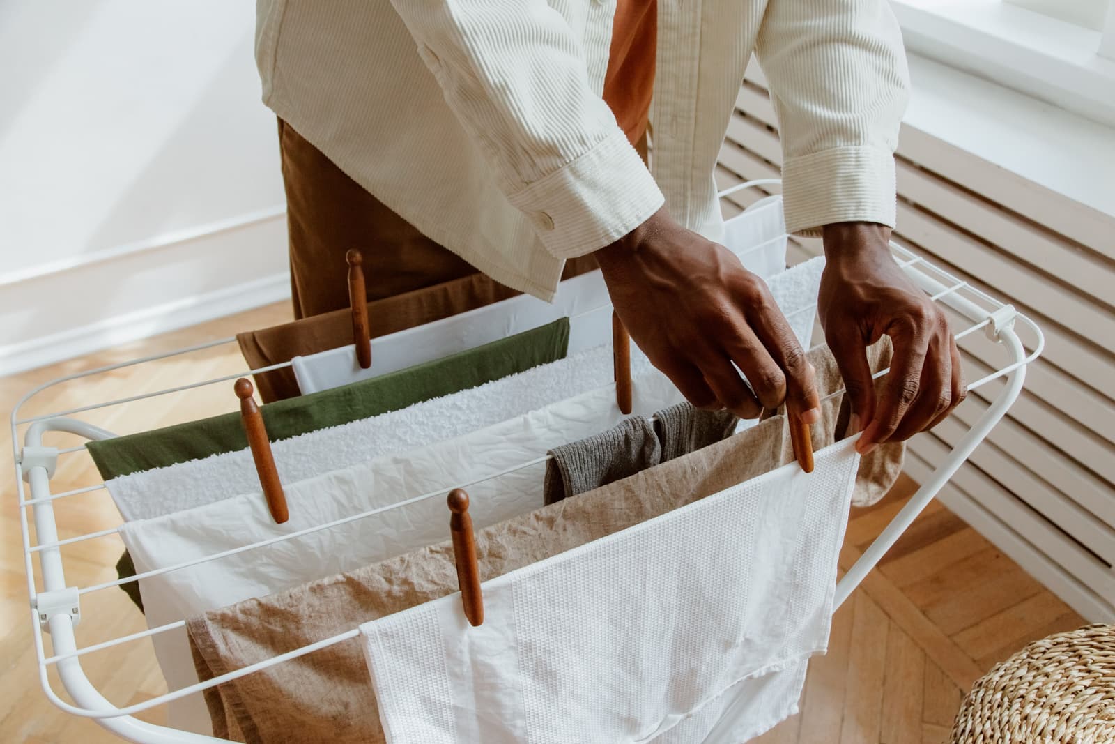 A metal folding clothes airer holding laundry in a naturally lit room