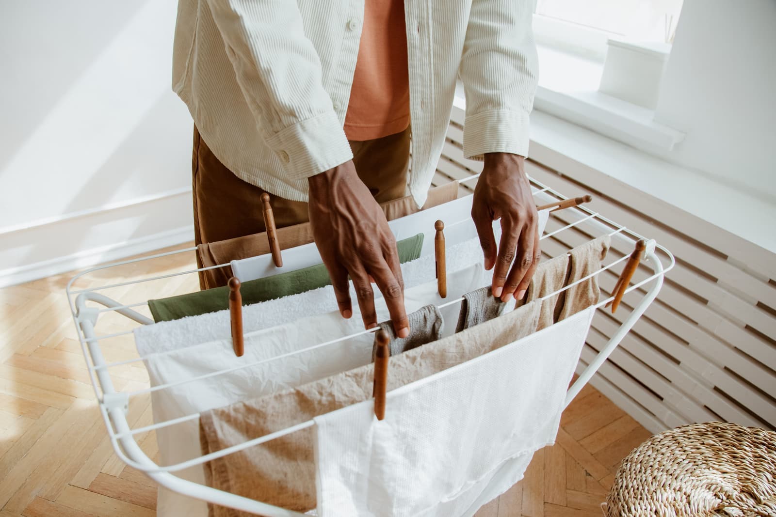 A folding clothes drying rack holding shirts in a bright apartment room